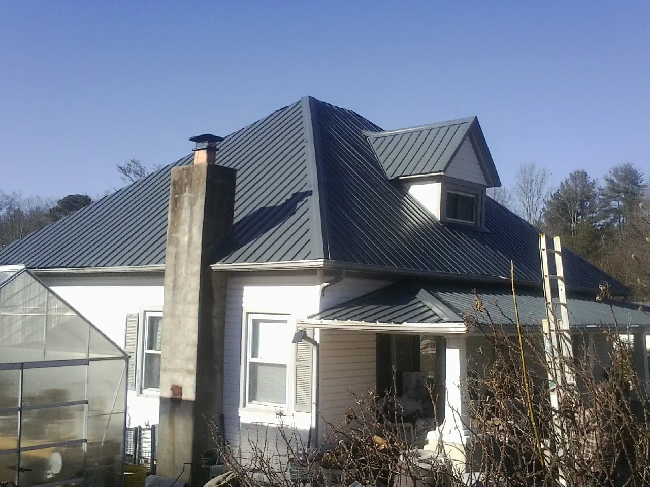 Dark blue standing seam metal roof on a white farmhouse with dormer — Slate & Tile Roof Repair by Roofing Brothers in Atlantic Highlands