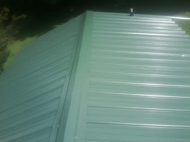 New green metal panels meeting at the ridge of a roof — Flat Roof Repair work by our crew in Atlantic Highlands