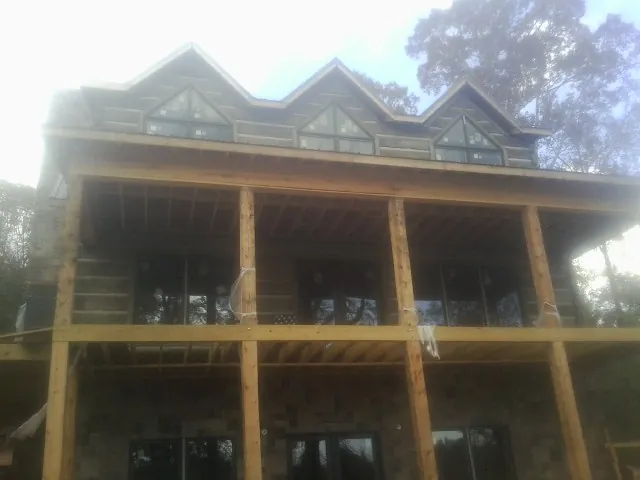 Dormers and porch framing on a large log home under construction — Roof Coating work by our crew in Atlantic Highlands