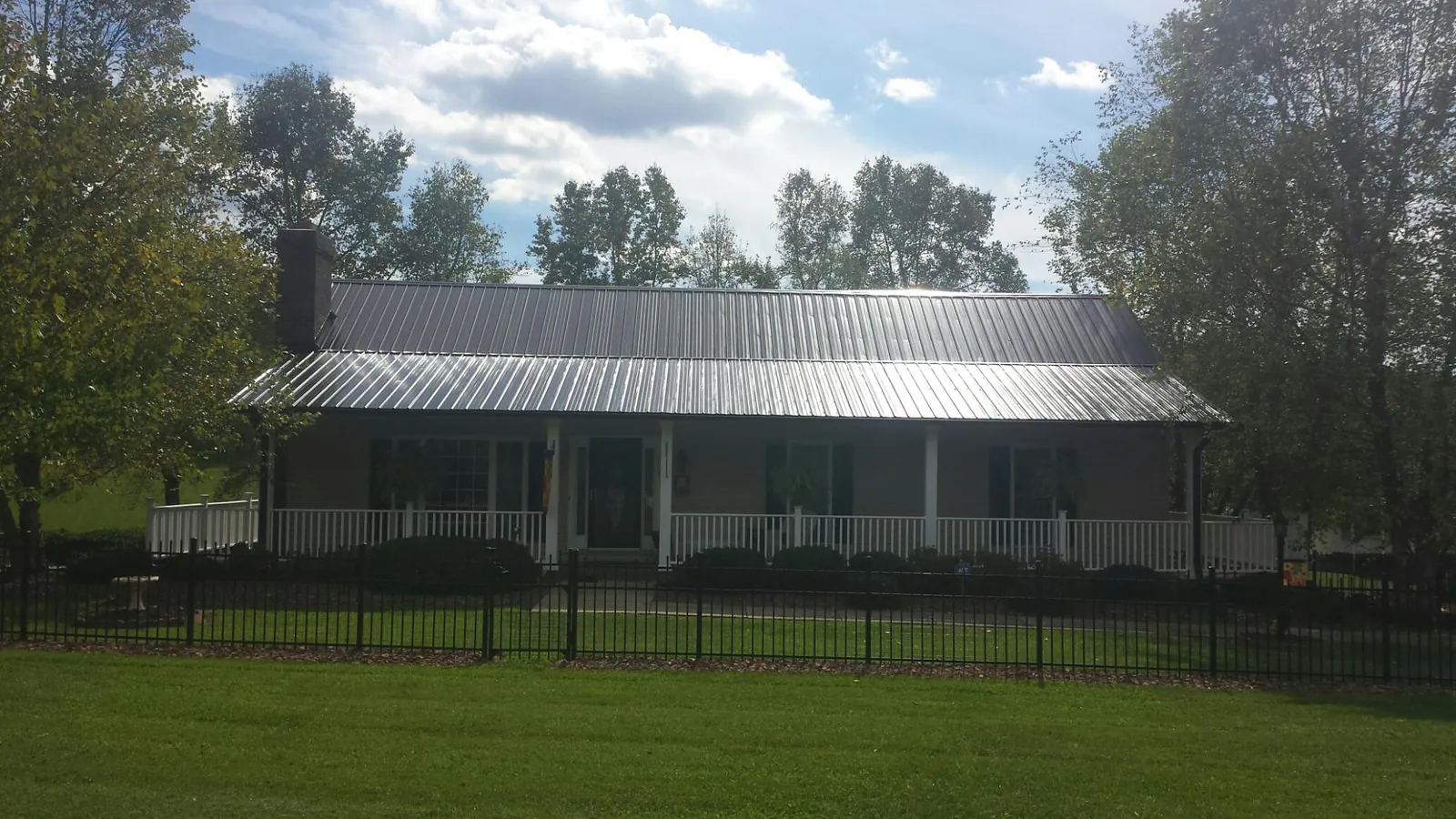 Gray metal roof on a brick ranch with a full width front porch — Gutter Guard Installation work by our crew in Atlantic Highlands