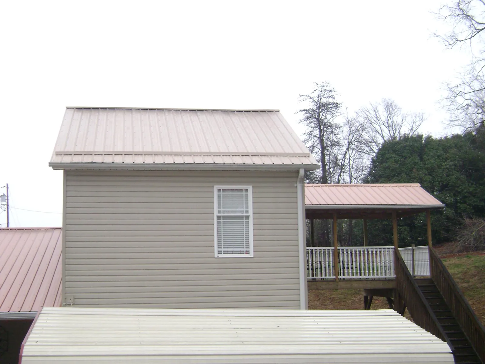 Tan metal roofs on a two story addition and attached porch, from a Roof Replacement job in Atlantic Highlands