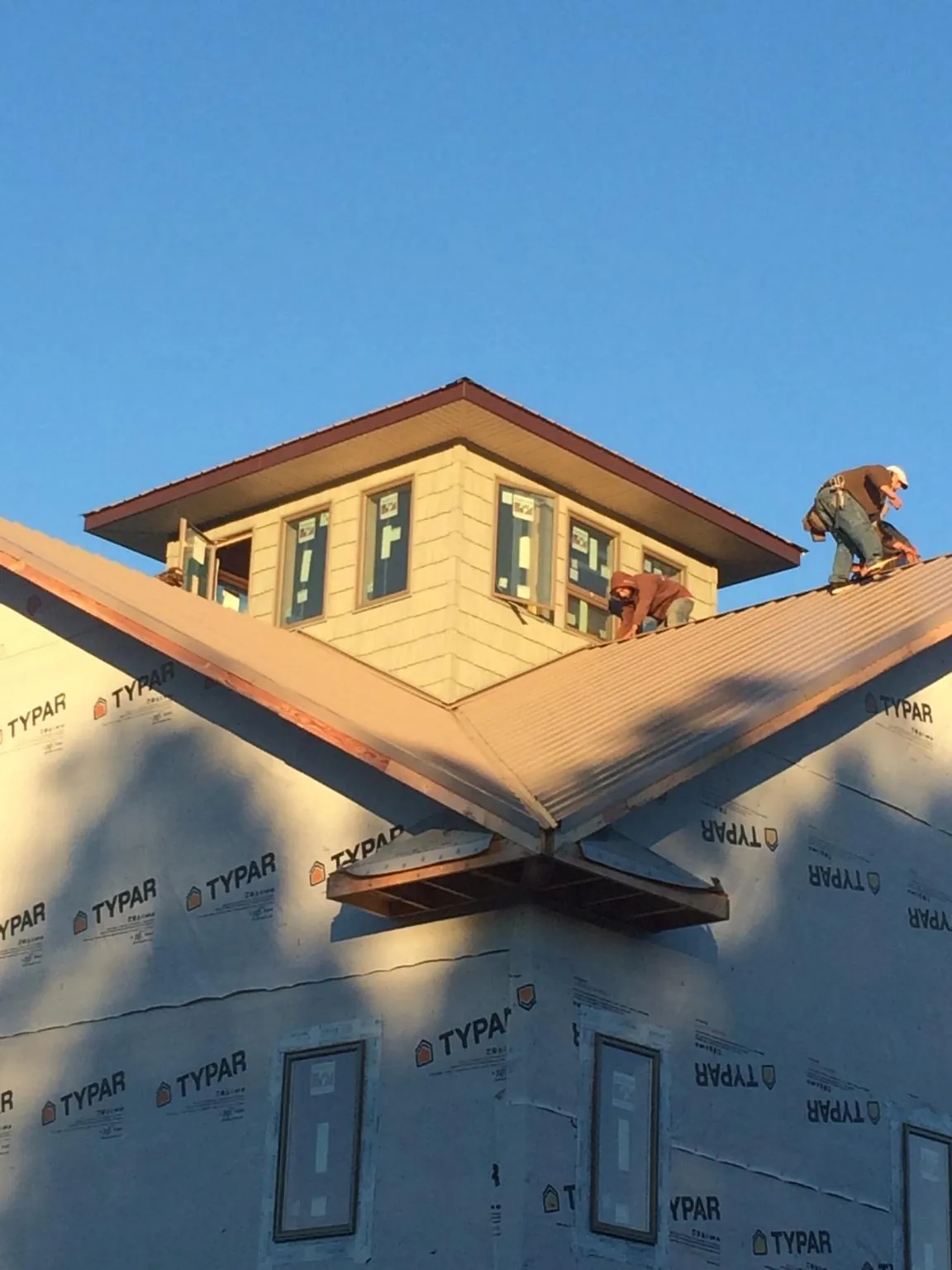 Roofers working around a rooftop cupola on a new metal roof at sunset — Roof Waterproofing in Atlantic Highlands by Roofing Brothers